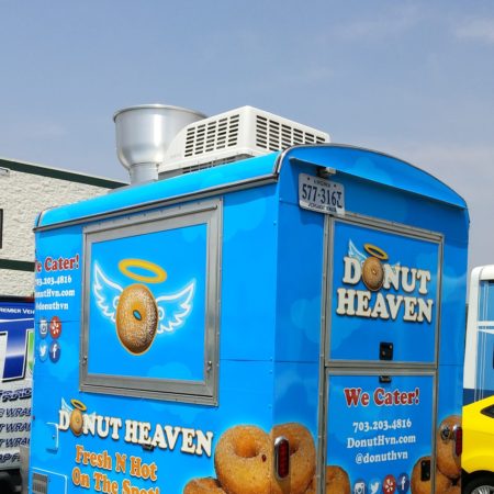 Donut Heaven food tractor parked behind a TradeWraps vehicle in an industrial parking lot