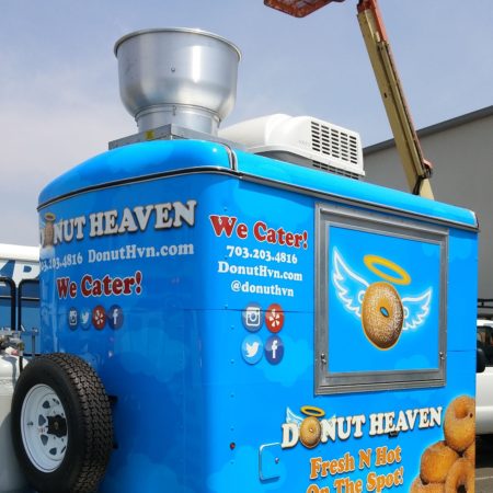 Donut Heaven food tractor parked in an industrial parking lot in front of a crane