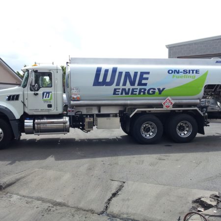 Gasoline truck for Wine Energy parked outside of a garage behind a building