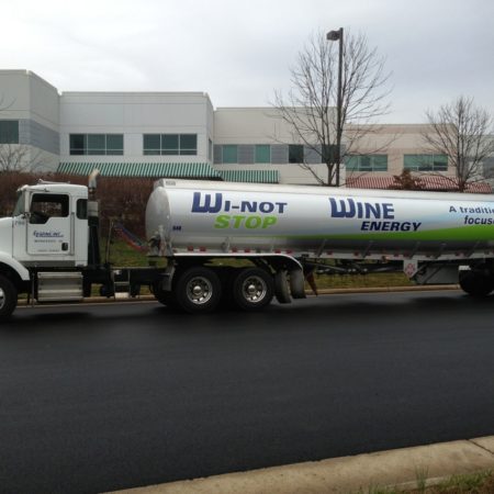 Gasoline truck parked next to building complex with wrapping for Wi-Not Stop Wine Energy