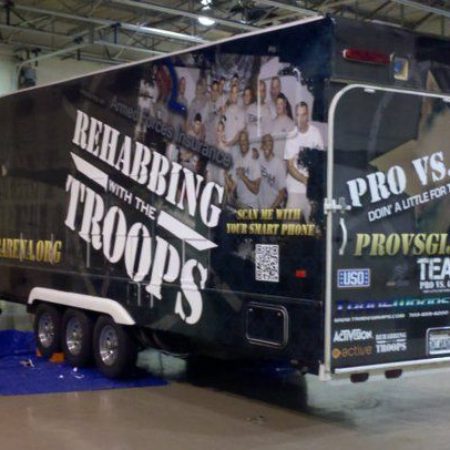 Trailer parked inside of a high school gym with wrapping for a military fundraiser