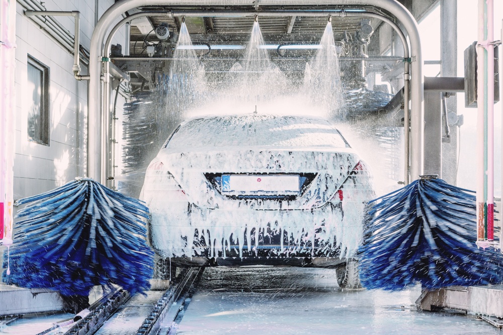 sedan covered in soap suds in the car wash